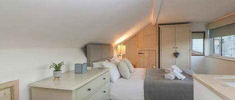 A bedroom with a bed, bedside table, lamp, and a window.
