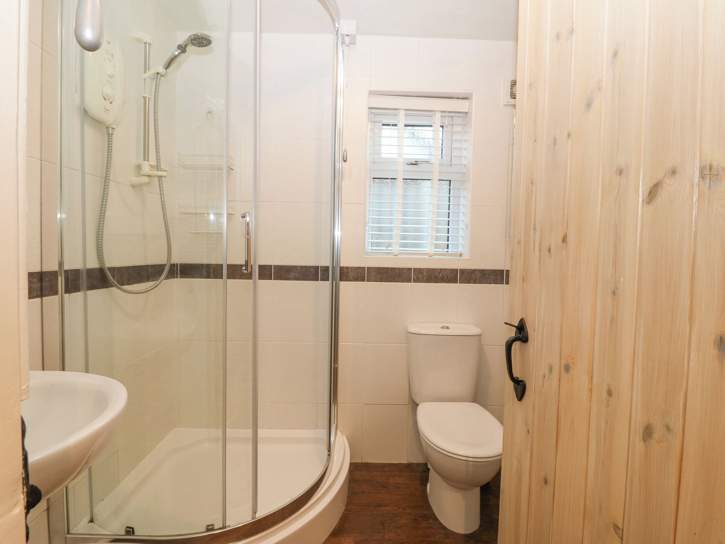 A bathroom with a glass-enclosed shower, a toilet, and a sink.