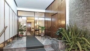 Un intérieur moderne avec un escalier en marbre, des portes en bois et des plantes en pot.