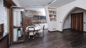 Une cuisine moderne avec un mur recouvert de pierres, un coin repas avec une table ronde et des chaises, et une bibliothèque remplie de livres.