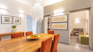 A dining area with a wooden table, orange chairs, and a bowl of fruit.
