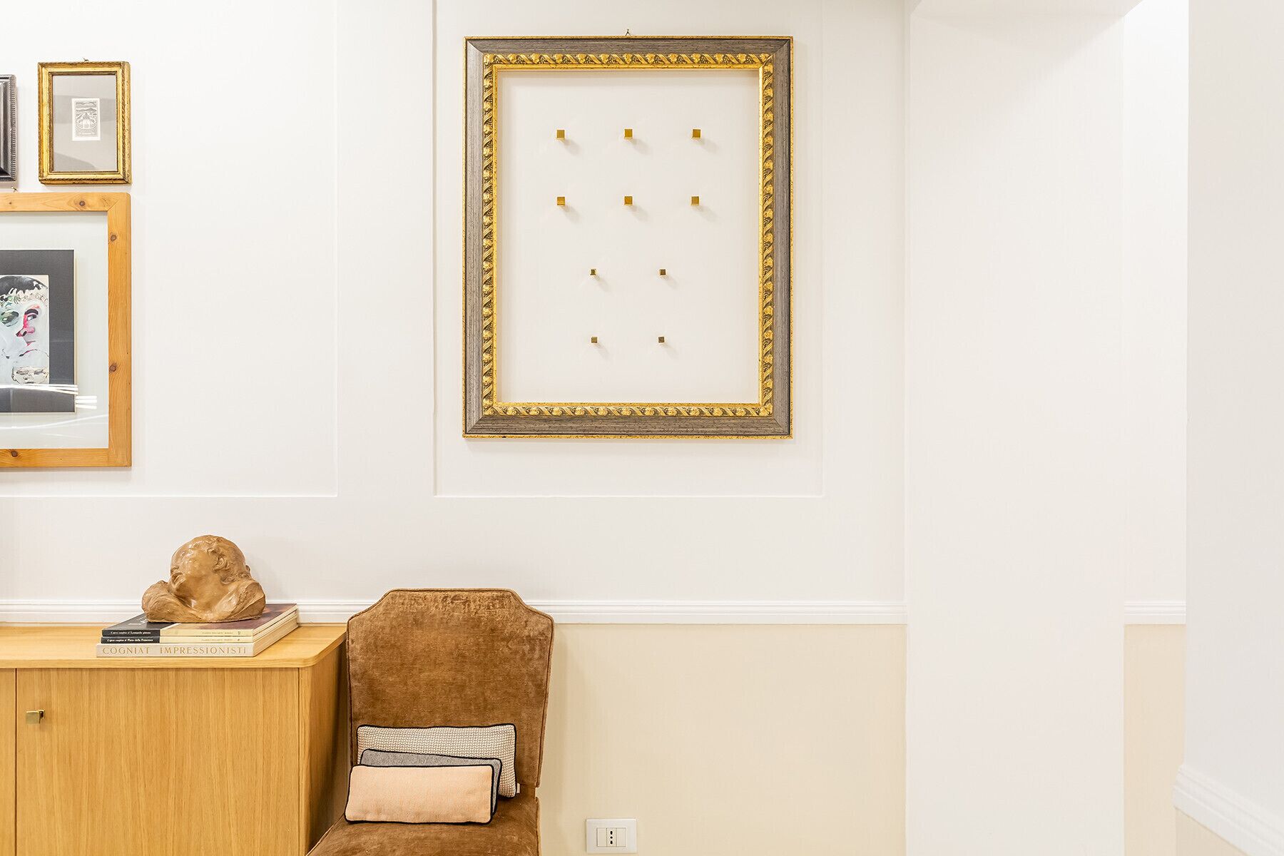 A room with a wooden cabinet, a brown chair, and a framed artwork on the wall.