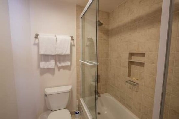 A bathroom with a glass-enclosed shower, a toilet, and a towel rack.