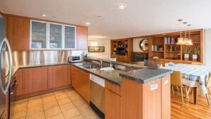 A modern kitchen with wooden cabinets, a built-in oven, and a dining area with a table and chairs. - Northwoods Private Condo with Easy Ski-In Ski-Out Access by RedAwning (Vail)