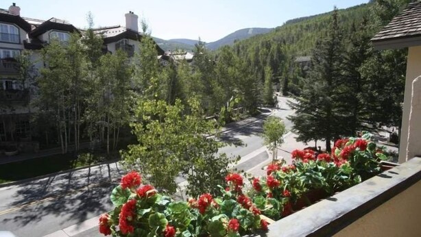 A residential area with a road, trees, and a building with a balcony. - 17 Vail Road Condos Short Walk to Vail Village and Gondola One by RedAwning (Vail)