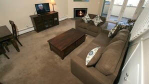 A living room with a television, fireplace, sofa, and a view of the outdoors. - 17 Vail Road Condos Short Walk to Vail Village and Gondola One by RedAwning (Vail)