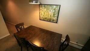 A dining area with a wooden table and chairs, a painting on the wall, and a lamp above the table. - 17 Vail Road Condos Short Walk to Vail Village and Gondola One by RedAwning (Vail)