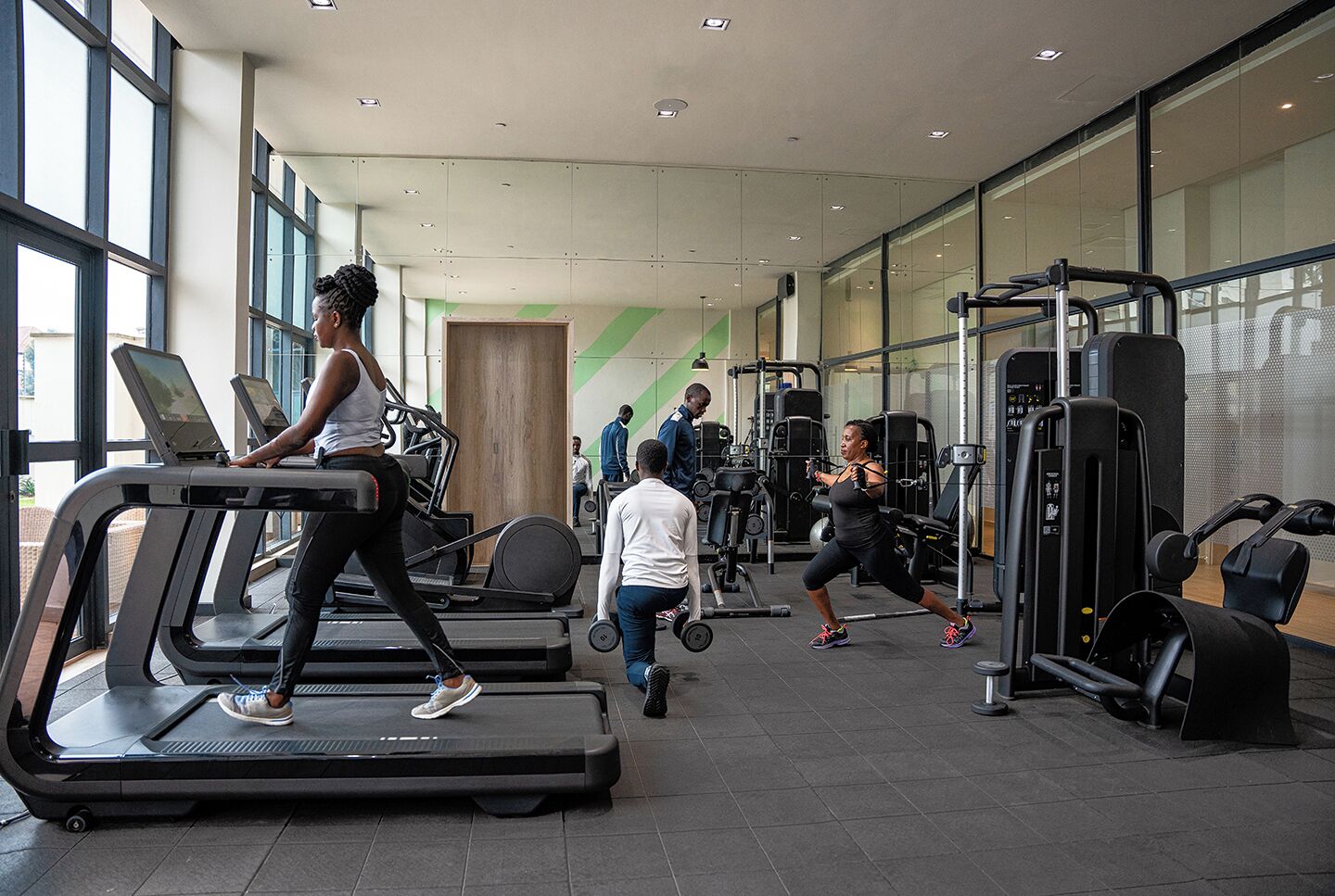 Un gimnasio con cintas de correr, máquinas de pesas y un amplio ventanal.