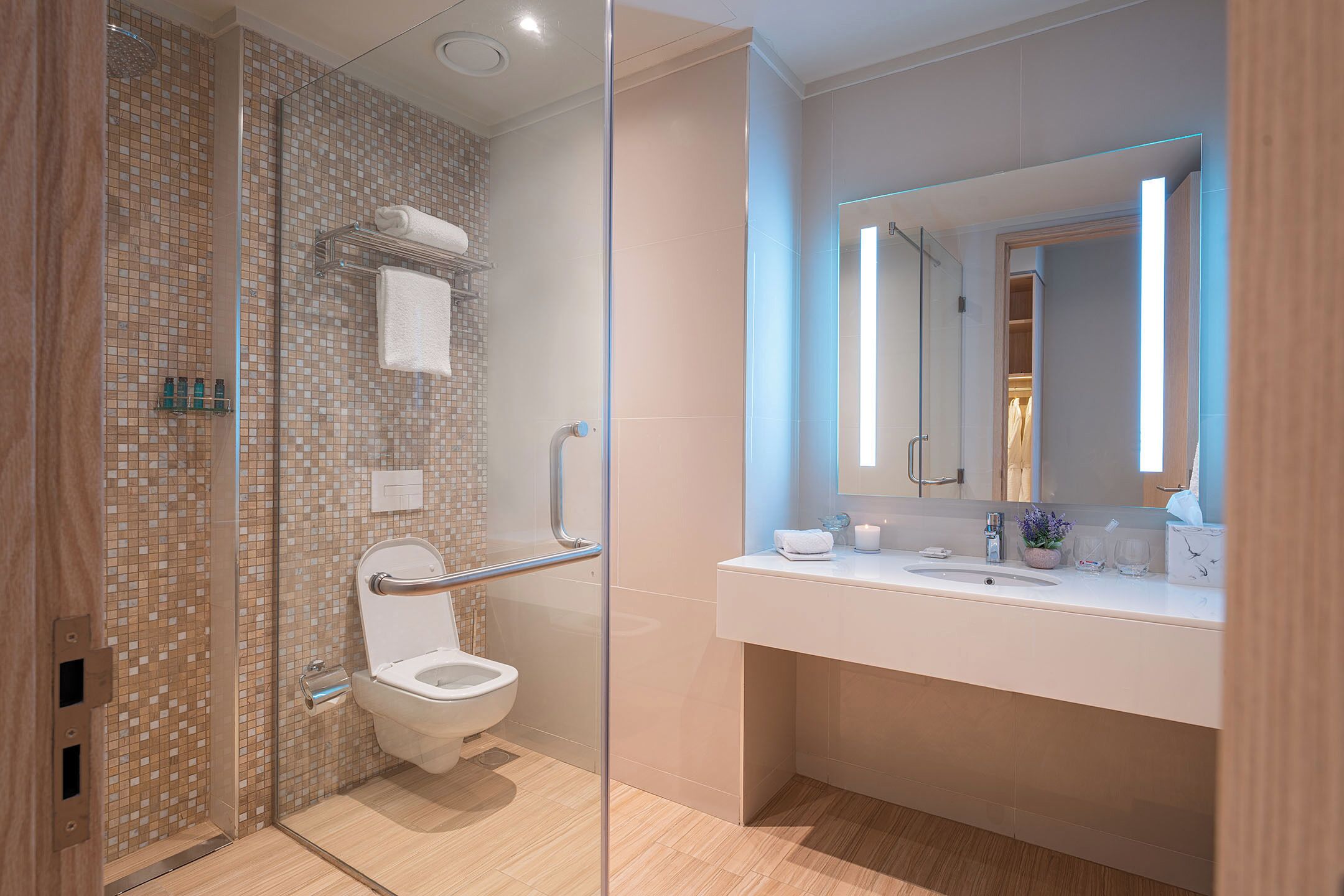 A modern bathroom with a glass shower enclosure, a white toilet, a sink with a mirror, and a towel rack.