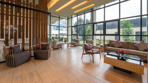 En rymlig entréhall med modern design, med en stor sittgrupp bestående av soffor och fåtöljer, ett soffbord och en dekorativ vägg med vertikala element.