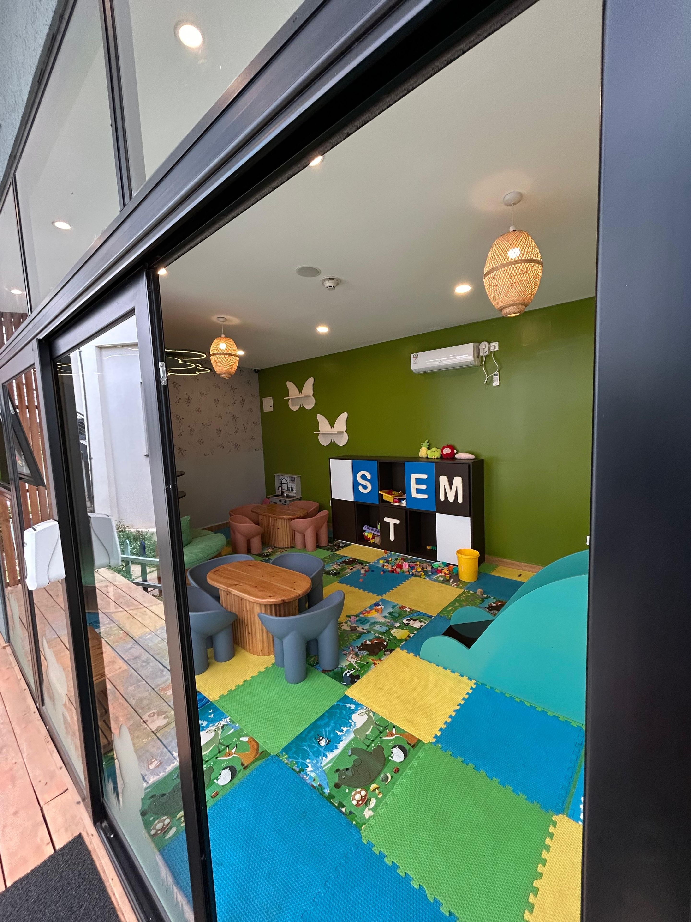 A children's playroom with a colorful play mat, seating, and educational toys.