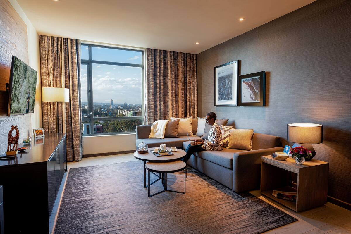 Ein modernes Wohnzimmer mit großem Fenster, einer Couch, einem Couchtisch und einem Fernseher.