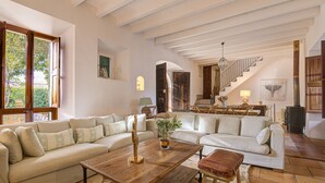 A spacious living room with a large sofa, a wooden coffee table, and a staircase leading to an upper level.