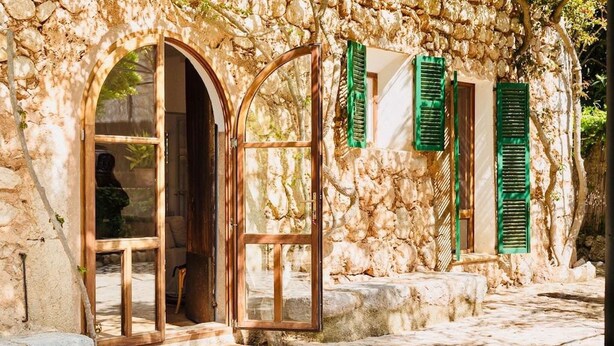 A stone building with arched doorways and green shutters.