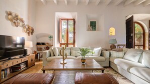 A living room with a television, sofa, coffee table, and leather ottomans.