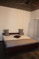 Una cama individual con estructura de madera, un ventilador de techo y una ventana con cortinas.