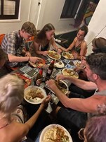 Un grupo de personas sentadas alrededor de una mesa con platos de comida y bebidas.