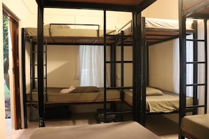 A bunk bed room with a window, a door, and a small stool.