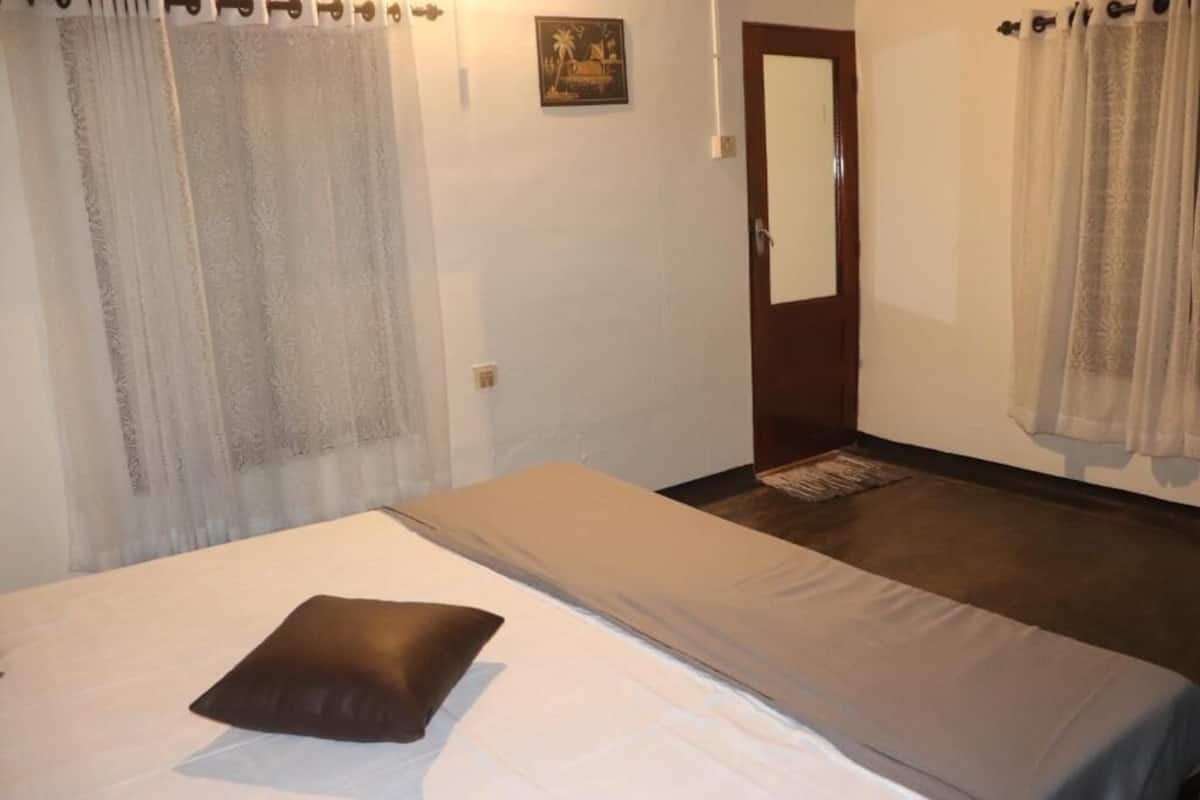 A bedroom with a bed, a door, and curtains.