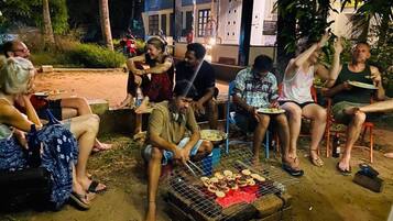 A group of people gathered around a grill outdoors at night.