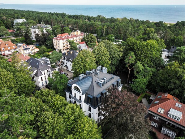 An aerial view of a residential area with various houses, surrounded by dense greenery and a beach in the background. - Apartamenty Swinoujscie - Villa 44 (Swinoujscie)