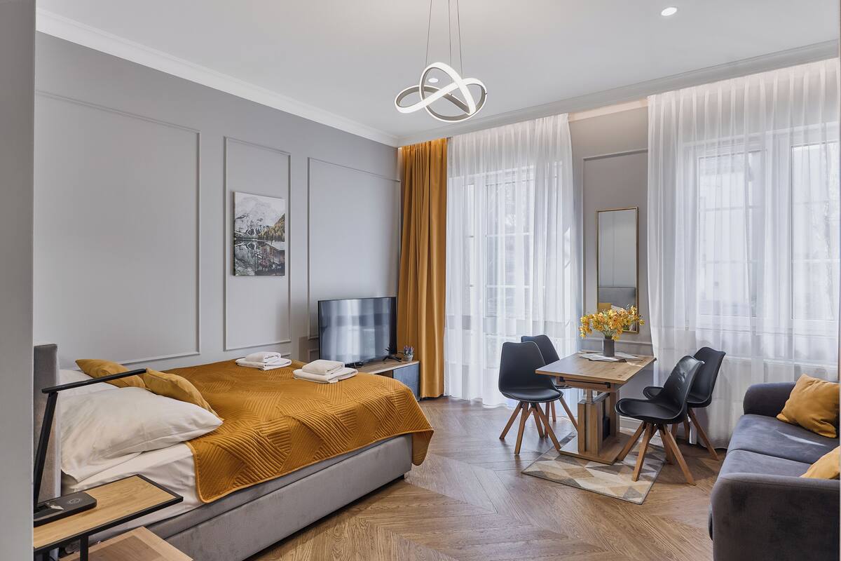 A modern hotel room with a bed, a desk, a TV, and a sofa.