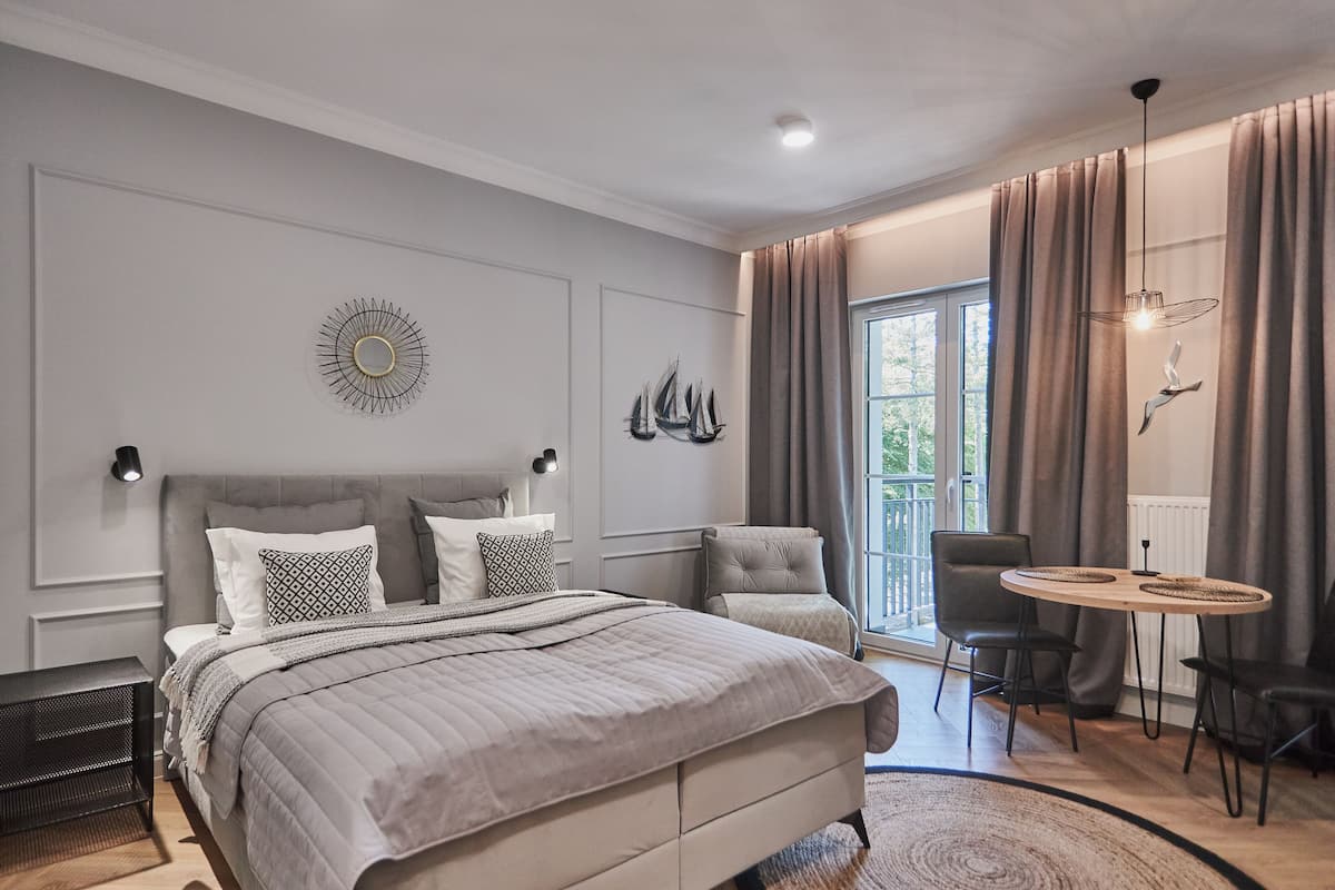A modern bedroom with a large bed, a small table, and a chair.
