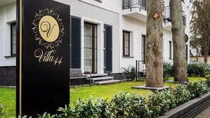 A sign for Villa 44 with a modern building in the background. - Apartamenty Swinoujscie - Villa 44 (Swinoujscie)