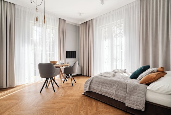 A modern hotel room with a bed, a desk, and a chair.