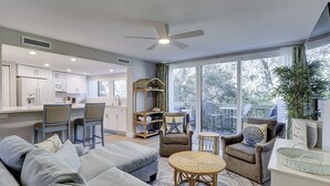 Ein modernes Wohnzimmer mit Sofa, Sesseln, Essbereich und einem Balkon mit Gartenmöbeln.