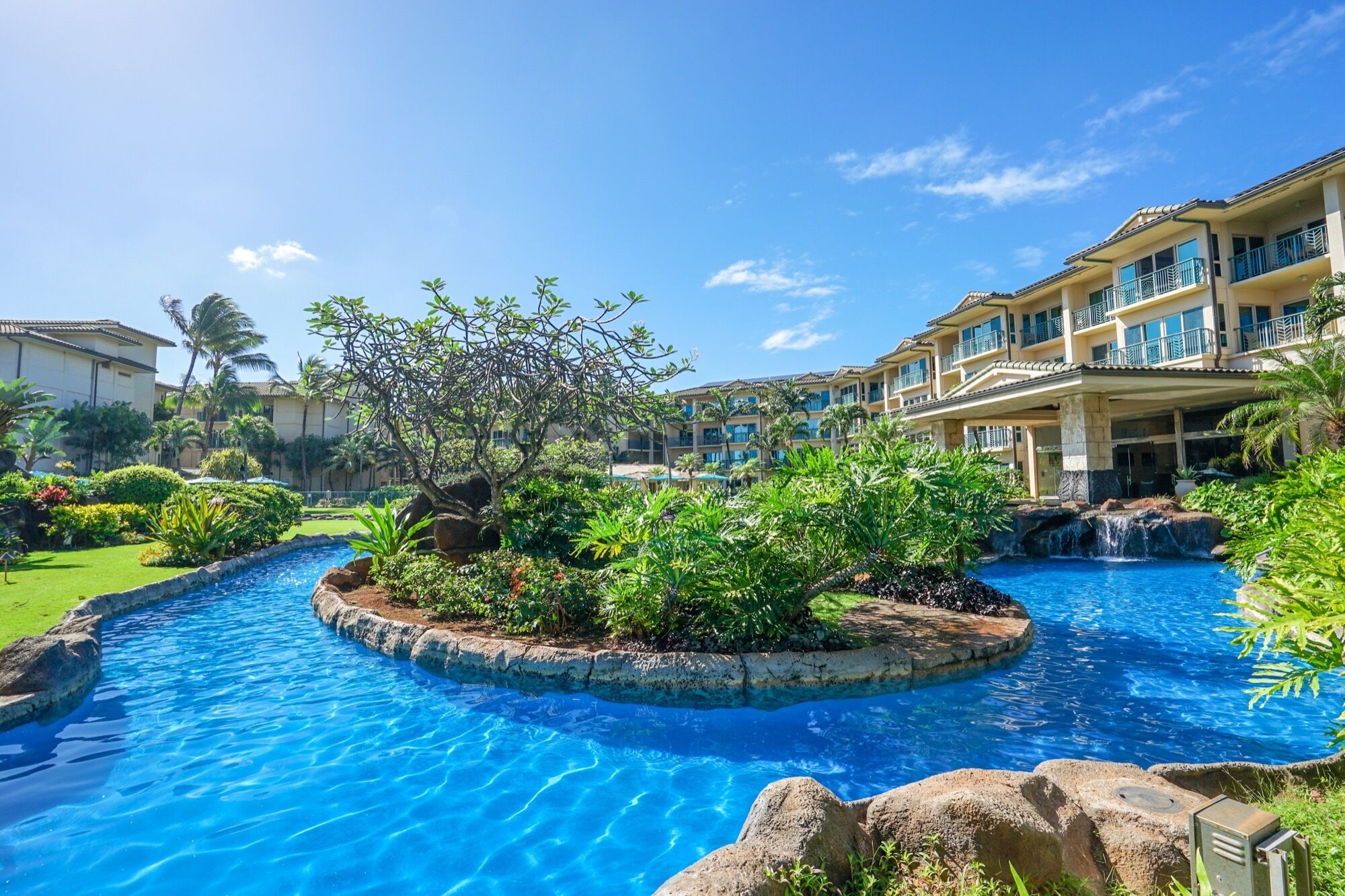A resort with a central swimming pool, lush landscaping, and multi-story buildings with balconies.