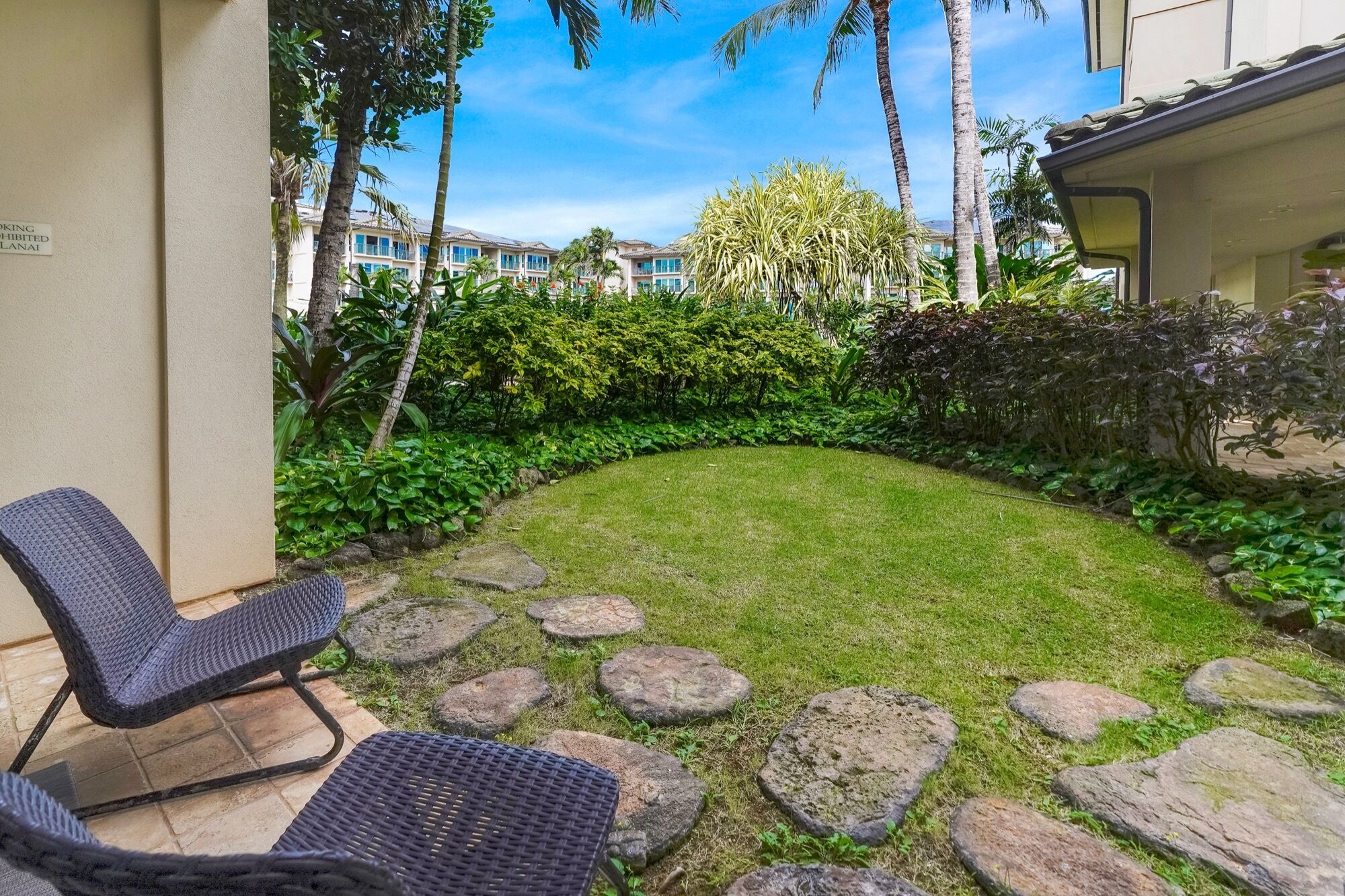 A well-maintained garden with a lawn, stone pathway, and outdoor seating area.