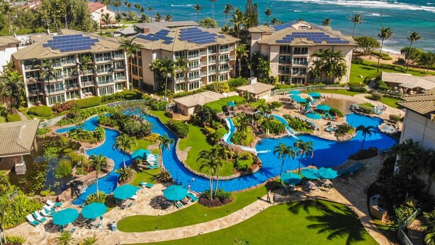 Un resort con varias piscinas, una amplia vista al océano y paneles solares en los edificios.