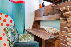 Rincón de una habitación con un escritorio de madera, una silla y una cama con colcha de lunares y diseño de hojas.