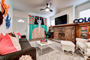 Una sala de estar con sofá, reposapiés, mesa de centro, chimenea y televisor.