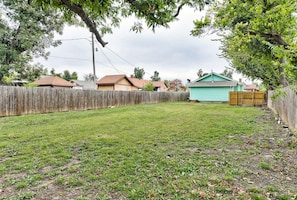 A backyard with a wooden fence, a green shed, and houses in the background.