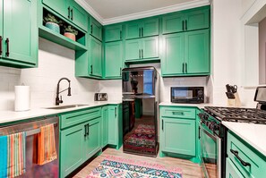 Una cocina con gabinetes verde azulado, un refrigerador de acero inoxidable, un microondas y una estufa.