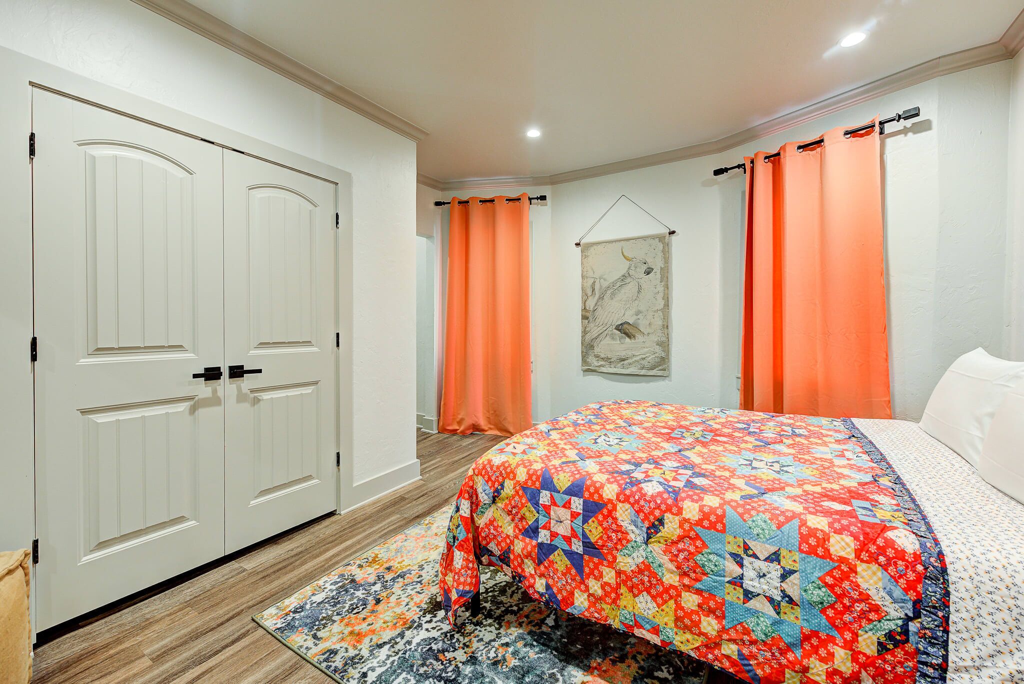 A bedroom with a bed, a door, and a wall-mounted artwork.