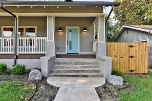 A house with a front porch, a blue door, and a wooden fence.