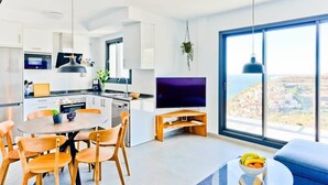 A modern kitchen with a TV, dining area, and large windows with a city view.