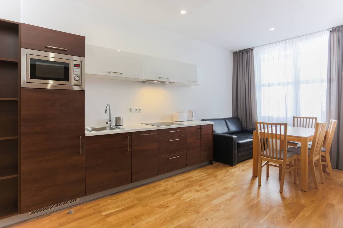 Una cocina moderna con microondas integrado, un fregadero y una zona de comedor con sillas y una mesa de madera.