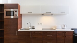 A modern kitchen with a built-in microwave, stainless steel sink, and white cabinets.