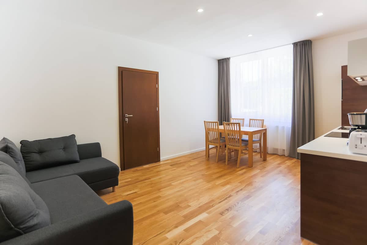 Una sala de estar moderna con un sofá, una mesa de comedor con sillas y una zona de kitchenette.