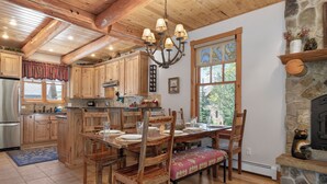A spacious kitchen with wooden cabinets, a dining table set for four, and a stone fireplace.
