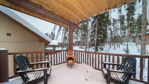 Una terraza de madera con dos sillas Adirondack y un estufa de leña.