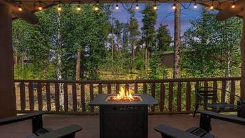 Une terrasse extérieure dotée d’un foyer, de rampes en bois et de deux bancs.