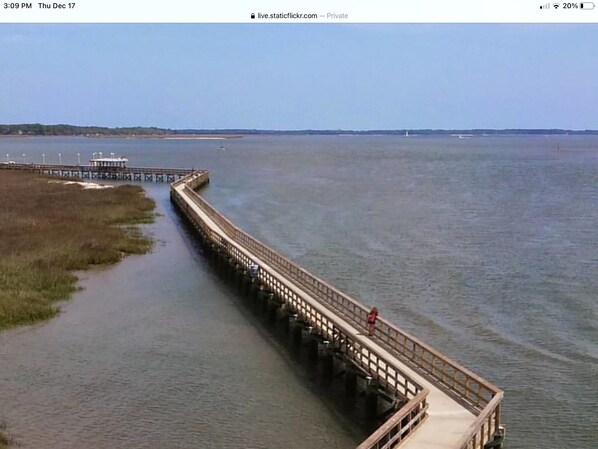 Eine hölzerne Pier, die sich in ruhiges Wasser erstreckt, während eine Person darauf geht.