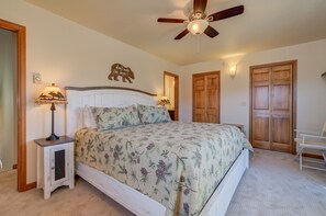 Un dormitorio con una cama, dos lámparas de noche, un ventilador de techo y puertas de madera.