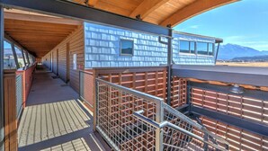 A covered outdoor area with a wooden ceiling, metal railings, and a view of a mountainous landscape.
