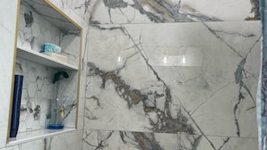 Une salle de bain avec des murs en marbre et un espace douche.